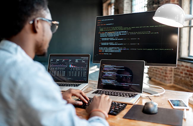 Coder working on multiple computers and monitors